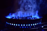 Blue gas flame burning on kitchen stove with dark background showing heat energy and cooking power in modern household appliance.