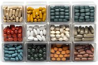 Assorted pharmaceutical pills and supplements in plastic organizer compartments showing various colors and shapes of medication capsules and tablets.