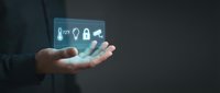 Businessman hand displaying glowing digital security icons including key, lightbulb, lock and shield representing cybersecurity and data protection concepts.