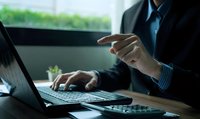 Professional businessman working on laptop computer at modern office desk with natural lighting for corporate business presentations.