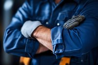 Professional mechanic in blue work uniform crossing arms showing expertise and confidence in automotive repair service industry.