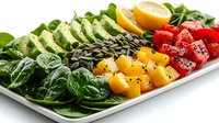 Fresh colorful salad bowl with avocado slices, spinach leaves, mango cubes, watermelon, pumpkin seeds and lemon on white rectangular plate. Healthy eating concept.