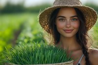 Young woman in straw hat holding basket of fresh wheatgrass against green summer background, natural wellness and healthy lifestyle concept.