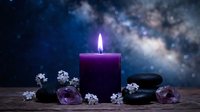 Purple candle burning with healing crystals and flowers against cosmic starry background for meditation, spirituality and wellness practices.