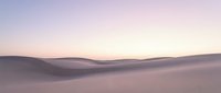 Serene desert landscape with rolling sand dunes under soft pastel sky at dawn or dusk, suitable for travel and nature backgrounds.