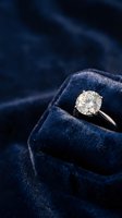 Elegant diamond solitaire engagement ring in luxurious navy blue velvet jewelry box for wedding proposal and romantic occasions.