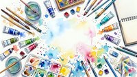 Overhead view of colorful watercolor paints, brushes, and art supplies arranged around vibrant splashes of blue, pink, and yellow pigment on white paper for creative projects.