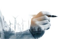 Double exposure of businessman hand writing with wind turbines and urban skyline, representing renewable energy investment and sustainable development planning.