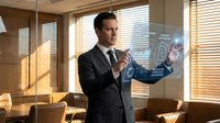 Professional businessman in dark suit interacting with futuristic holographic interface displaying data analytics in modern office with natural lighting.