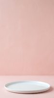 Empty white ceramic plate on soft pink textured background, ideal for product display, cosmetics presentation, and minimalist design mockups.