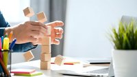 Caucasian male hands stacking wooden blocks on office desk, symbolizing business strategy, planning, and growth concept.