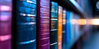 Row of vintage leather-bound books on shelf with colorful spines in purple, blue and gold tones, captured with shallow depth of field creating dreamy bokeh effect.