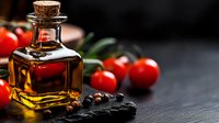 Fresh cherry tomatoes and olive oil bottle on dark stone background with spices, dramatic food photography style for restaurant menu and cooking blogs.
