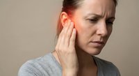 Middle-aged Caucasian woman experiencing ear pain, touching her ear with concerned expression. Healthcare concept showing earache or hearing problems.