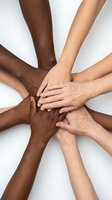 Diverse hands of different ethnicities stacked together in unity circle showing teamwork collaboration and racial equality on white background.