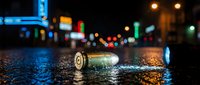 Urban night scene with discarded beer bottle on wet asphalt street reflecting colorful neon lights from bars and shops in blurred background cityscape.