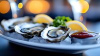 Fresh oysters on ice with lemon wedges and cocktail sauce, served on white plate for fine dining, seafood restaurant, and gourmet cuisine.