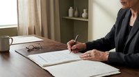 Professional businesswoman signing important legal documents at wooden desk in modern office environment for corporate agreements.