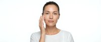 Young Caucasian woman applying skincare cream to face with gentle touch, natural beauty routine and facial care concept for cosmetic advertising.