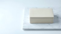 Minimalist beige rectangular storage box with lid placed on white marble surface against clean white background for modern home organization.