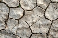 Cracked dry soil texture with deep fissures forming natural pattern. Drought-affected earth surface showing environmental impact of climate change and arid conditions.