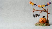 Festive autumn holiday decoration featuring carved pumpkin, hanging spider, and Happy Halloween banner on textured background. Perfect for seasonal marketing and holiday design projects.