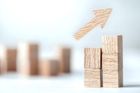 Wooden blocks arranged in ascending order with arrow pointing upward symbolizing growth, success and progress on light background. Business concept.