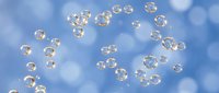 Soap bubbles floating against blue sky with white clouds creating dreamy atmosphere for relaxation and childhood memories concepts.