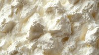 Fresh cottage cheese macro texture with soft curds and creamy white surface showing natural dairy food structure and nutritious protein-rich detail.