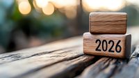 Wooden blocks showing number 2026 on rustic wooden surface with soft bokeh lights in background, symbolizing future planning and business vision.