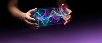 Hands holding glowing neon waveform display with colorful digital sound waves on dark background for music production and audio technology concepts.