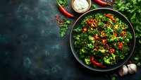 Fresh broccoli salad with red chili peppers and garlic served in black bowl on dark background with herbs and sauce, healthy vegetarian meal.