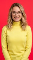 Smiling young Caucasian woman with blonde wavy hair wearing glasses and yellow turtleneck sweater against bright red background for lifestyle content.