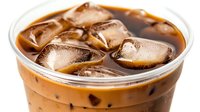 Refreshing iced coffee with milk in clear plastic cup, close up view of cold brew coffee drink with ice cubes floating in creamy brown liquid.