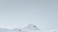 Snow-covered mountain peak rising against overcast sky in arctic wilderness landscape for travel and nature editorial projects.