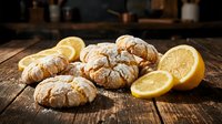 Fresh baked lemon crinkle cookies with powdered sugar dusting arranged on rustic wooden table with lemon slices for baking and dessert concepts.