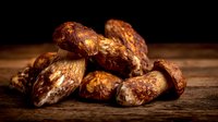 Fresh porcini mushrooms with brown caps on rustic wooden table against dark background, ideal for gourmet cooking and food photography.