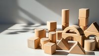 Natural wooden building blocks scattered on white surface with dramatic shadows for educational play and creative construction activities.