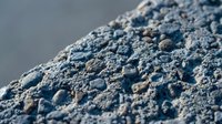 Rough textured concrete surface with porous holes and weathered finish for industrial construction and architectural design projects.