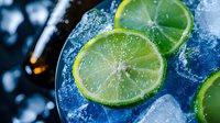 Fresh lime slices with ice cubes in cocktail glass for summer drinks and beverage preparation.