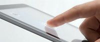 Close-up of a finger touching a tablet screen, showing a glowing tap point on a sleek device, symbolizing digital interaction and technology.