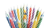 Colorful striped birthday candles with one lit candle glowing in the center, isolated on white background for celebration and party designs.