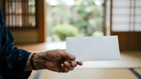 Senior male with brown skin tone holding blank white card indoors, suitable for business messaging, greeting cards, promotional campaigns, and corporate communications.