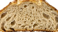 Sliced bread cross-section showing soft, airy crumb structure with irregular holes and golden-brown crust, suitable for food photography, bakery marketing, and culinary publications.
