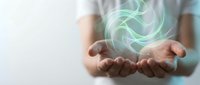 Businessman holding glowing green energy swirl in cupped hands representing renewable power, sustainability, and environmental innovation concepts.