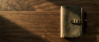 Vintage brass wallet and pen on wooden surface with warm sunlight casting shadows, suitable for business, finance, and lifestyle design projects.