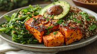 Grilled tofu with quinoa salad, avocado and fresh greens on rustic plate. Healthy vegan protein meal for plant-based diet and wellness lifestyle.