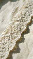 Cream lace trim with delicate floral embroidery on natural fabric, isolated on white background for wedding, fashion, and textile design projects.