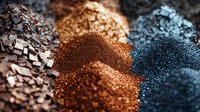 Colorful makeup pigments and crushed eyeshadow powders in brown, blue and metallic shades create abstract textured pattern. Close up macro photography of cosmetic products.