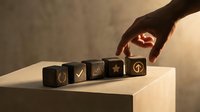 Hand placing wooden cube with arrow symbol among business icons on minimalist surface representing strategic decision making and growth direction.
